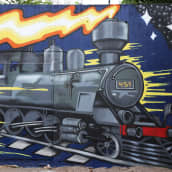 Kouvolan rautatieaseman alikulkutunnellin uloskäynnin seinämään maalattua muraalitaidetta.