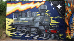 Kouvolan rautatieaseman alikulkutunnellin uloskäynnin seinämään maalattua muraalitaidetta.