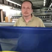 Printscorpion toimitusjohtaja Tommi Helminen pitelee Ukrainan lippua.