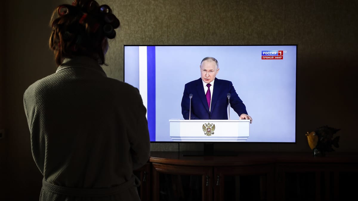 Nainen katsoo televisiosta, kun Venäjän presidentti Vladimir Putin pitää puhettaan Moskovassa 21. helmikuuta 2023.