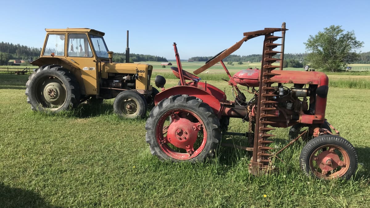 Kaksi vanhaa traktoria pellolla.