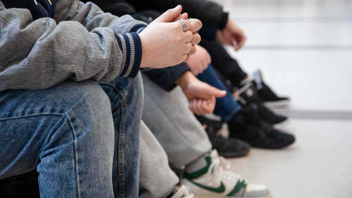 Anonyymeja 7.-luokkalaisia poikia istumassa Lauritsalan koulun käytävällä.