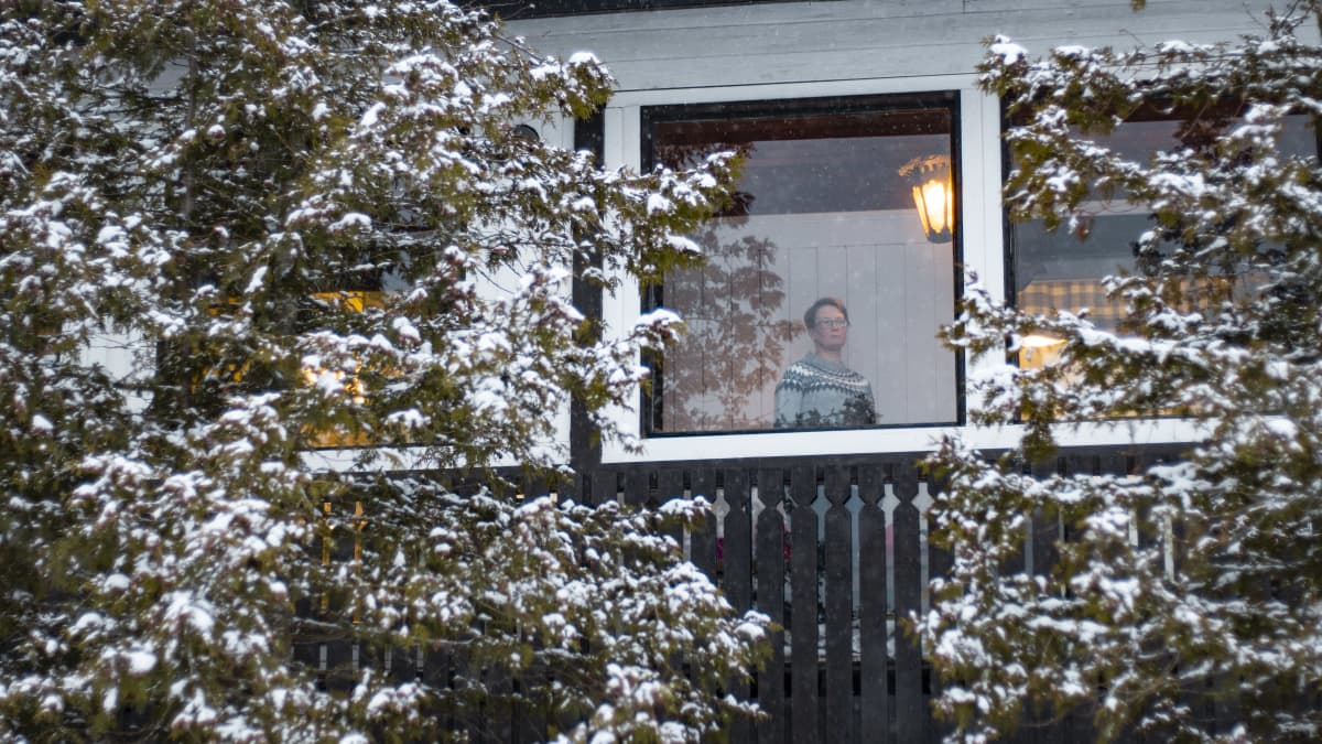Kuvassa Kirsi Vuorela, katsoo kotinsa ikkunasta ulos. 