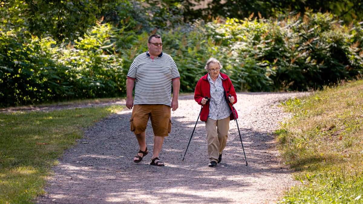 Markku Kostiainen kävelyllä puistossa iäkkään äitinsä Raili Kostiaisen kanssa.