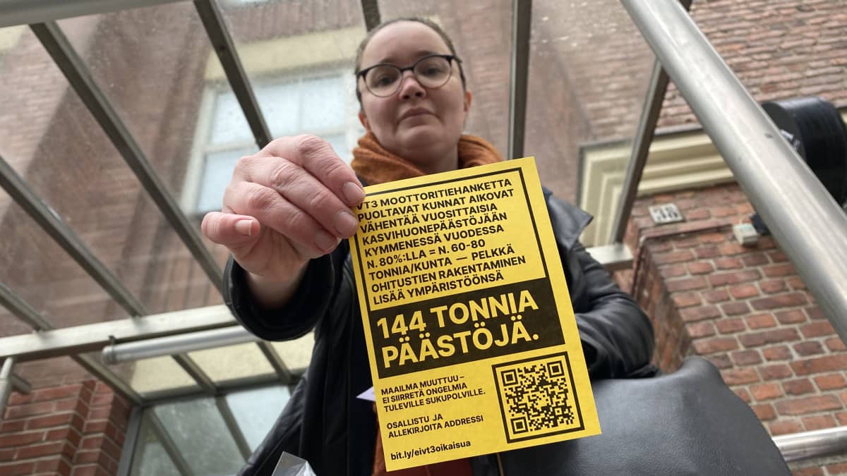 Kirsi Riihijärvi, Lempäälä näyttää kameralle keltaista paperia, jossa kerrotaan moottoritiehankkeen ongelmista.