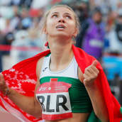 Krystsina Tsimanouskaja kääriytyneenä Valko-Venäjän lippuun.