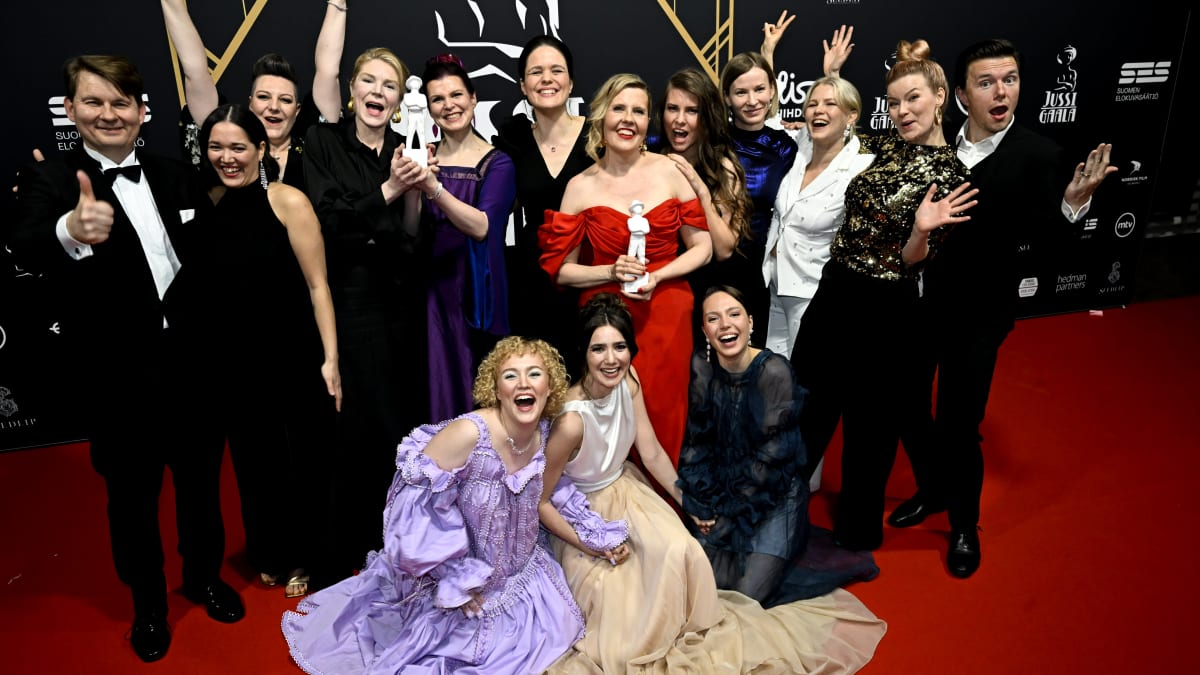 Tytöt, tytöt, tytöt -elokuvan työryhmä poseeraa yhdessä Jussi-patsaan kanssa.