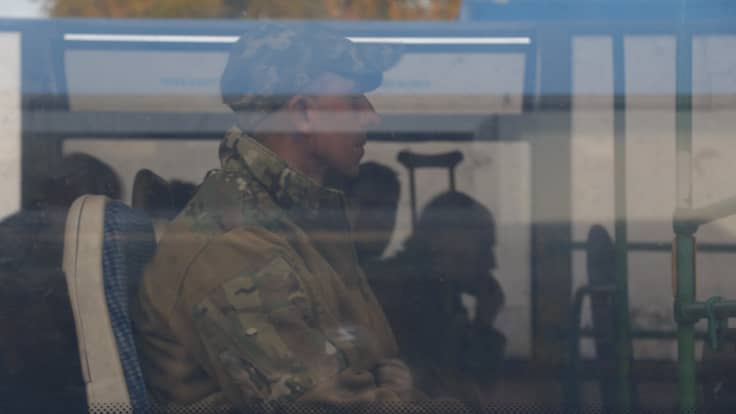 Antautunut sotilas istuu bussissa. Kuva on otettu bussin ulkopuolelta.