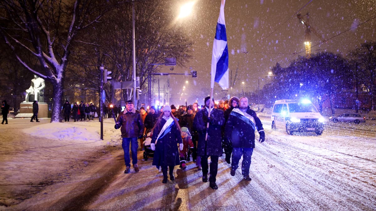 Mielenosoittajat kulkevat soihtuja ja suomenlippu kädessään.