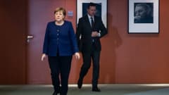Angela Merkel ja Steffen Seibert kävelevät lehdistötilaisuuteen Saksassa maaliskuussa.
