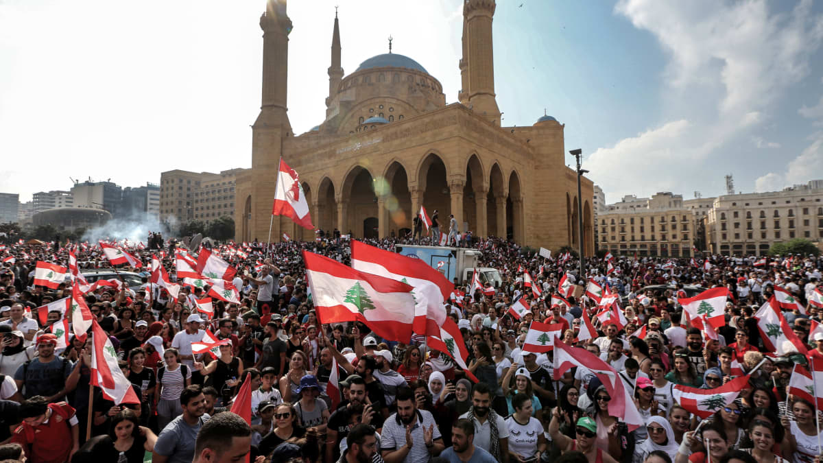 Lippuja liehuttava valtava ihmisjoukko taustalla moskeija.