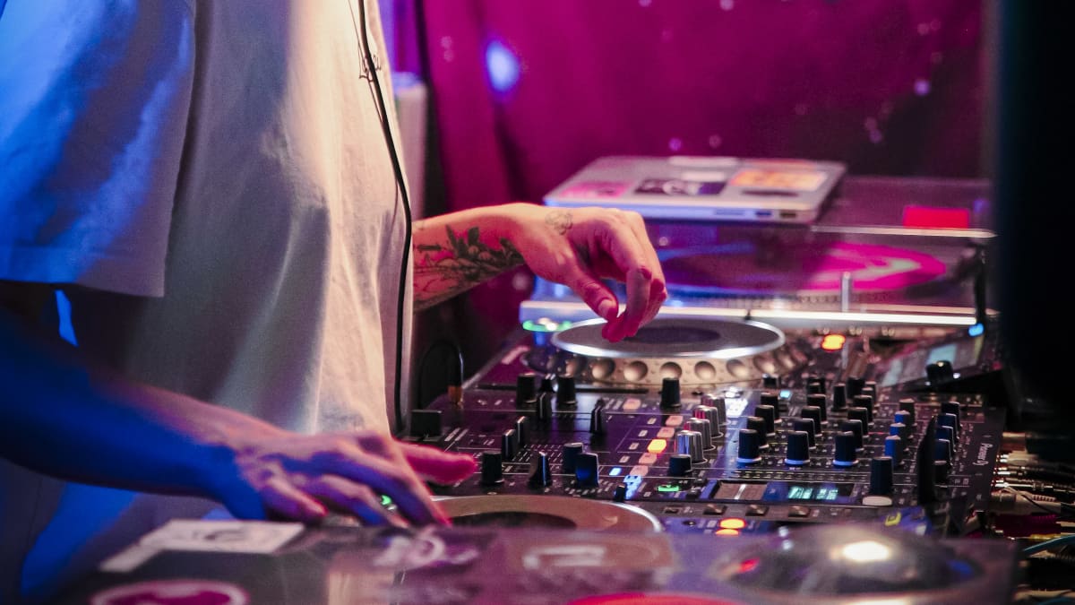 Tia soittaa kuulokkeet korvilla musiikkia dj-pöydällä.