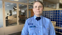 Poliisin asuun pukeutunut katsoo kameraan.