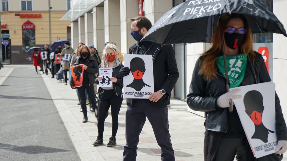 Szczecin kaupungissa kasvosuojiin pukeutuneet mielenosoittajat vastustavat lakialoitteita jonottamalla kaupan edustalla 14. huhtikuuta 2020. Jonottamalla he eivät riko koronaviruksen takia asetettua kokoontumisrajoitusta.