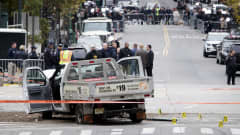 Terrori-iskun tekemiseen käytetty auto on ovet auki kadun varressa rikospaikalla, jota useat poliisit tutkivat.
