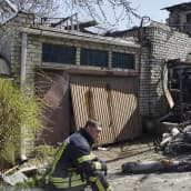 Pelastustyöntekijä istuu vaurioituneen rakennuksen edessä.