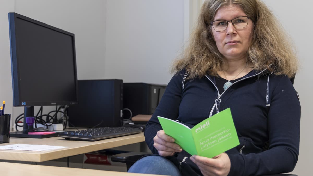 Länsi-Pohjan sairaanhoitopiirin psykologi Elina Valkonen lukee Mieli ry:n esitettä työhuoneessaan.