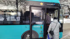 Kuopion paikallisliikenteen linja-auto ja siihen nousevia matkustajia.