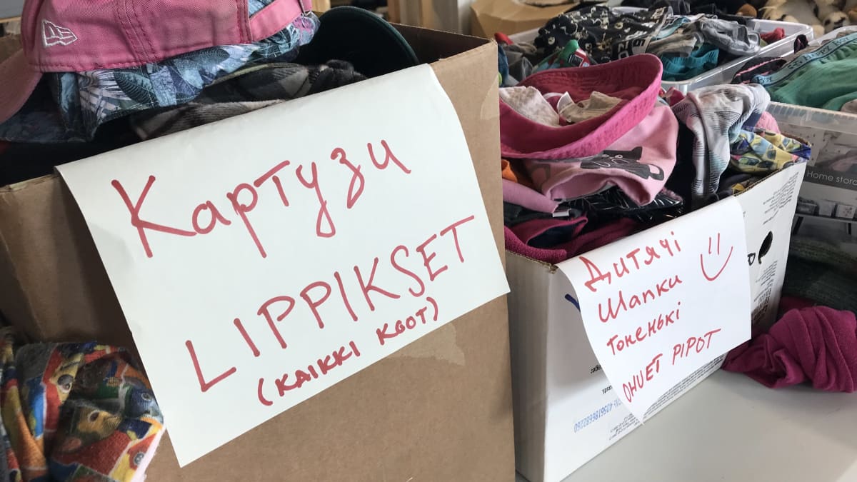 Pahvilaatikoita, joissa lippalakkeja, ja toisessa pipoja ukrainalaisille pakolaisille. Laatikossa tekstit suomeksi ja ukrainaksi. 