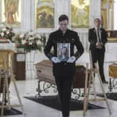 Miehet pitävät vainajien kuvia Ukrainan Odessassa järjestyissä hautajaisissa.