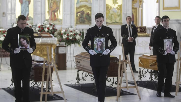 Miehet pitävät vainajien kuvia Ukrainan Odessassa järjestyissä hautajaisissa.