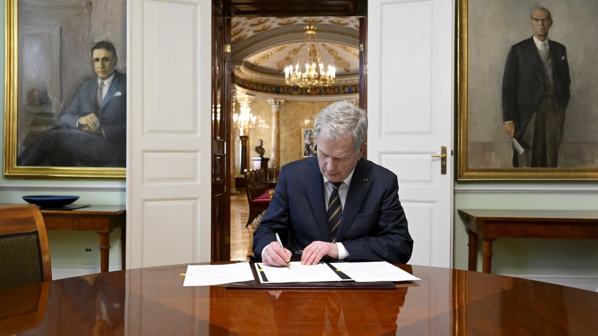 Sauli Niinistö allekirjoittaa dokumenttia.