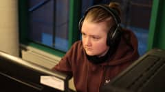 Sanna Lassila istuu kuulokkeet päässä tietokoneen ääressä editoimassa nuorisotalo Mondella Rovaniemellä.