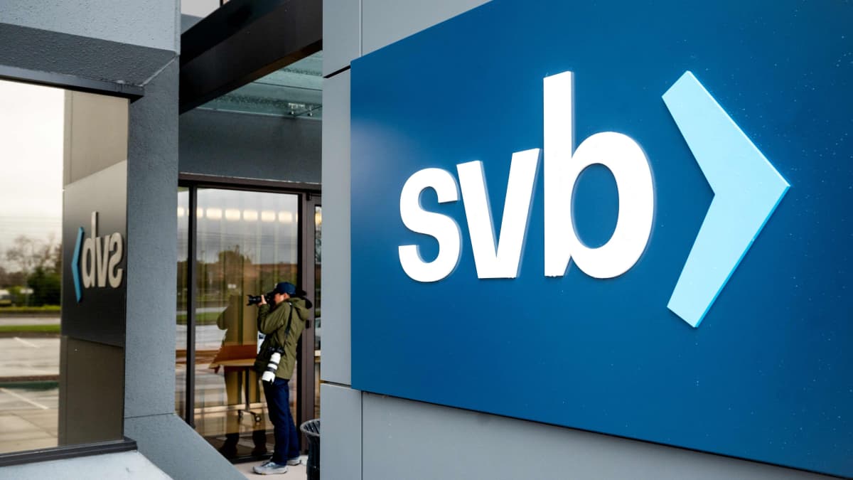 SVB-pankin logo on pankin pääkonttorin aulan seinällä, valkoista tekstiä sinisellä pohjalla. Aulassa näkyy valokuvaaja.