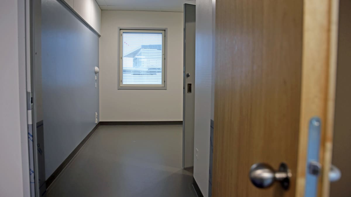 Näkymä nuorten psykiatrisen osaston huoneeseen, joka on kalustamaton. Vasemmalla sininen seinä, huoneen perällä ikkuna.