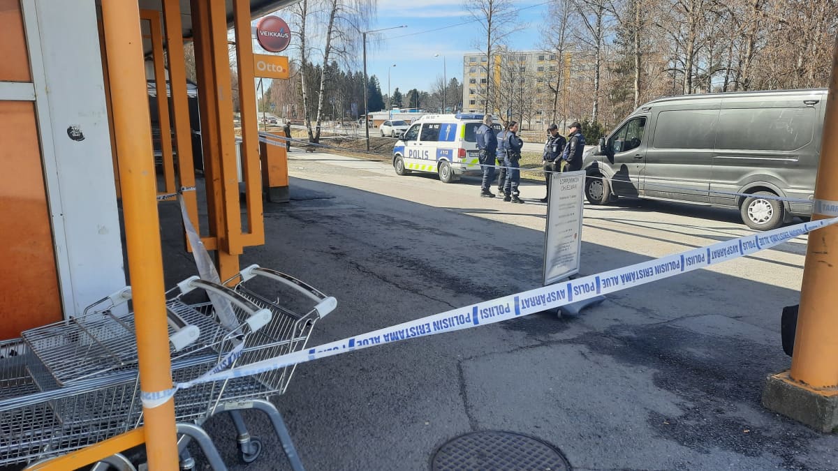 Kaupan edessä eristysnauhaa ja poliiseja sekä poliisiauto,