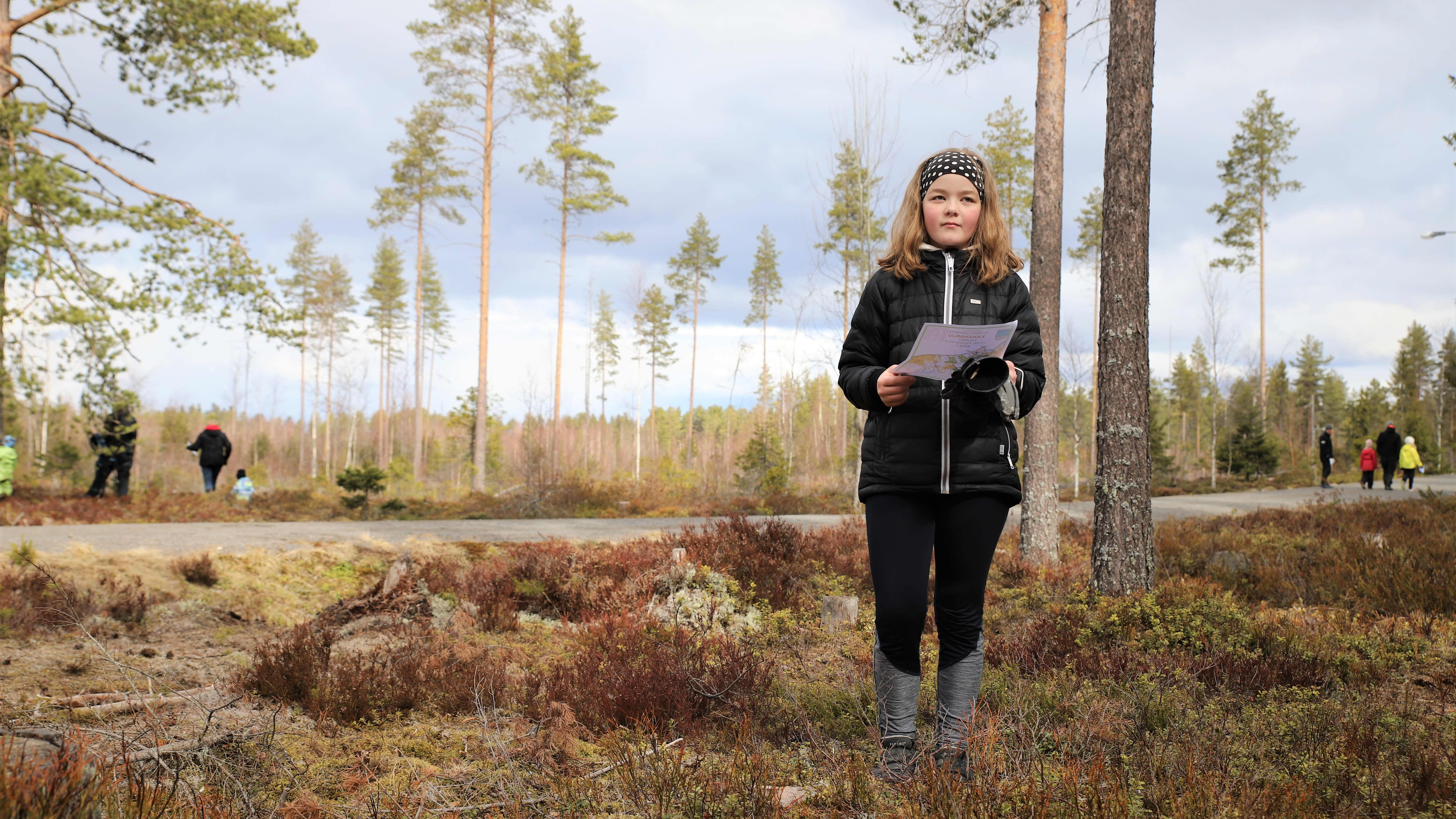 Anni Penninkangas seisoo kartan kanssa metsässä Alajärven kuntoradan maastossa