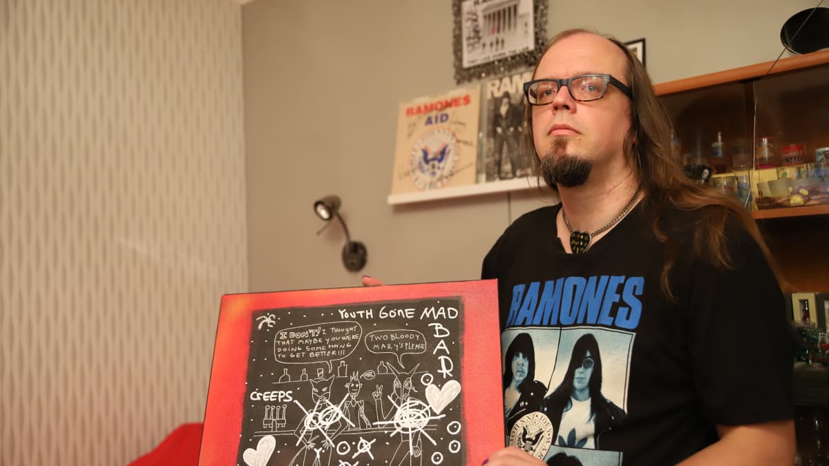 Jari-Pekka Laitio-Ramone pitelee kädessään Dee Dee Ramonen maalaamaa taulua.