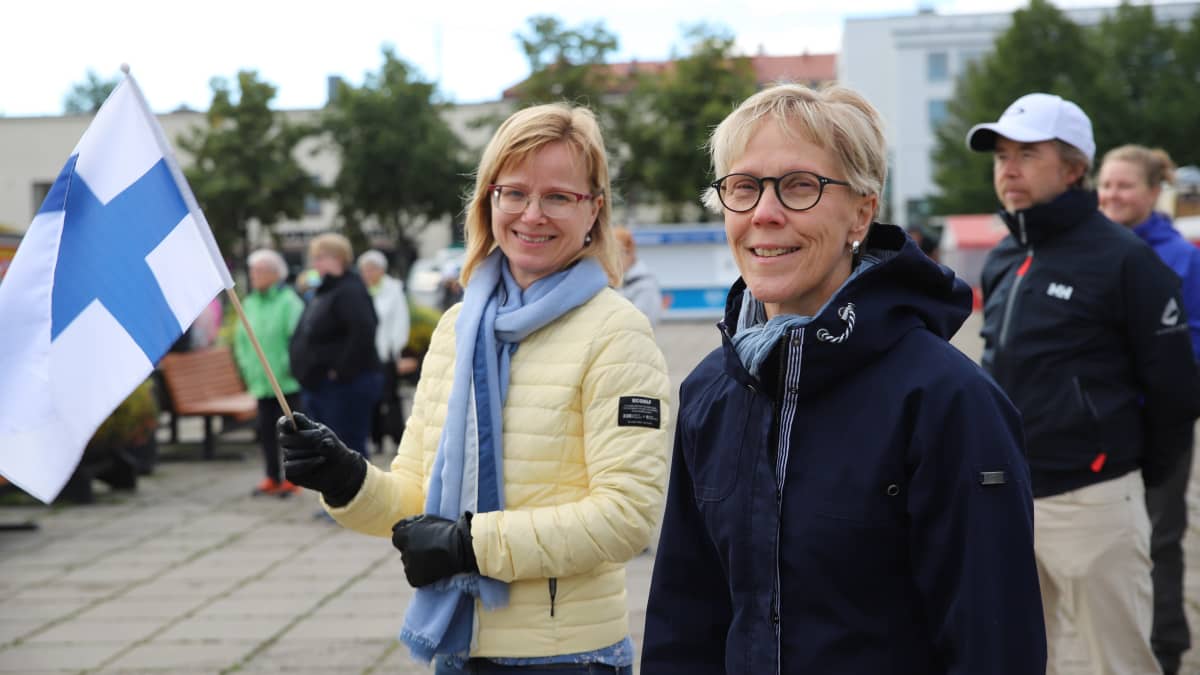Teija Pääkkönen ja Tuula Rajaniemi seisovat Kokkolan torilla Suomen lippu kädessä