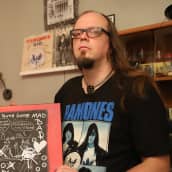 Jari-Pekka Laitio-Ramone pitelee kädessään Dee Dee Ramonen maalaamaa taulua.