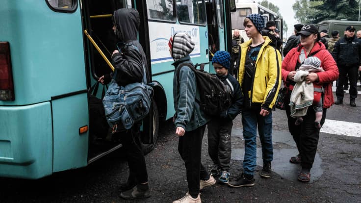 Ihmiset jonottava pääsyä linja-autoon.