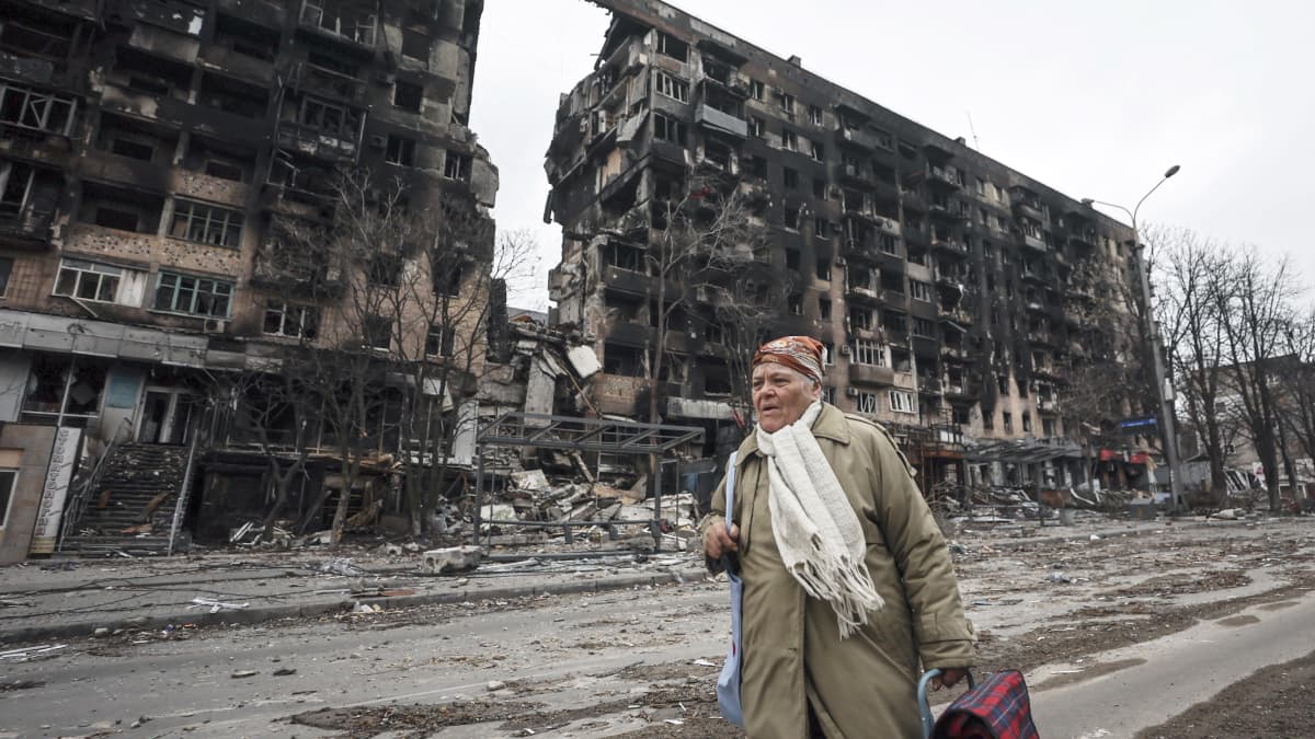 Nainen kävelee tuhoutuneen rakennuksen edustalla Mariupolissa.