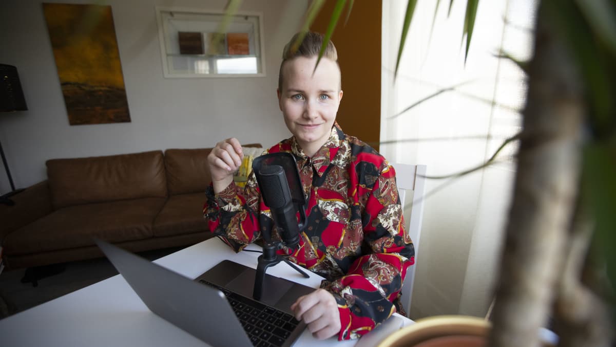 Sonja Huhtaniska on tietokoneen ja mikrofonin äärellä oman kotinsa olohuoneessa.
