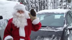 Riku Oikarinen, 21, on pukeutunut joulupukiksi ja vilkuttaa kameralle. Hänen takanaan on auto ja luminen maisema.