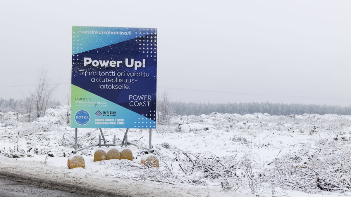 Kyltti, jossa lukee "Power Up! Tämä tontti on varattu akkuteollisuuslaitokselle." Taustalla talvinen hakkuualue.