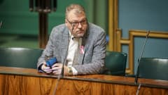 Kokoomuksen kansanedustaja Jari Kinnunen istumassa omalla paikallaan eduskunnan istuntosalissa.