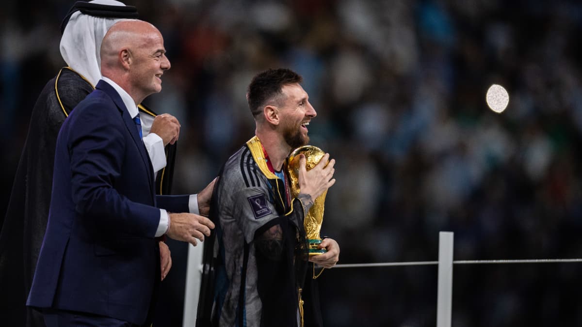Lionel Messi kävelee MM-pokaali sylissään. Fifan puheenjohtaja Gianni Infantino ja Qatarin emiiri Tamim bin Hamad Al Thani katsovat perään.