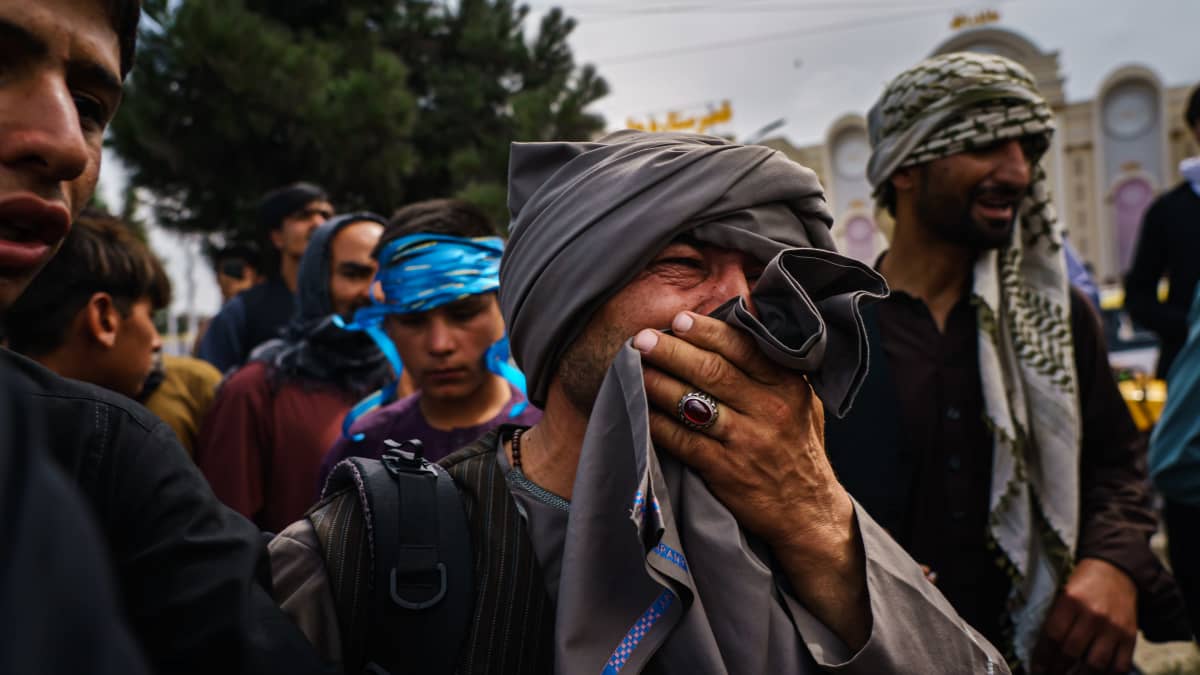 Mies suree kaaoksessa loukkaantuneita ihmisiä Kabulin kansainvälisen lentokentän ulkopuolella tiistaina 17. elokuuta.