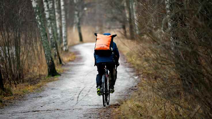A cyclist travels down a frosty dirt road in autumn.