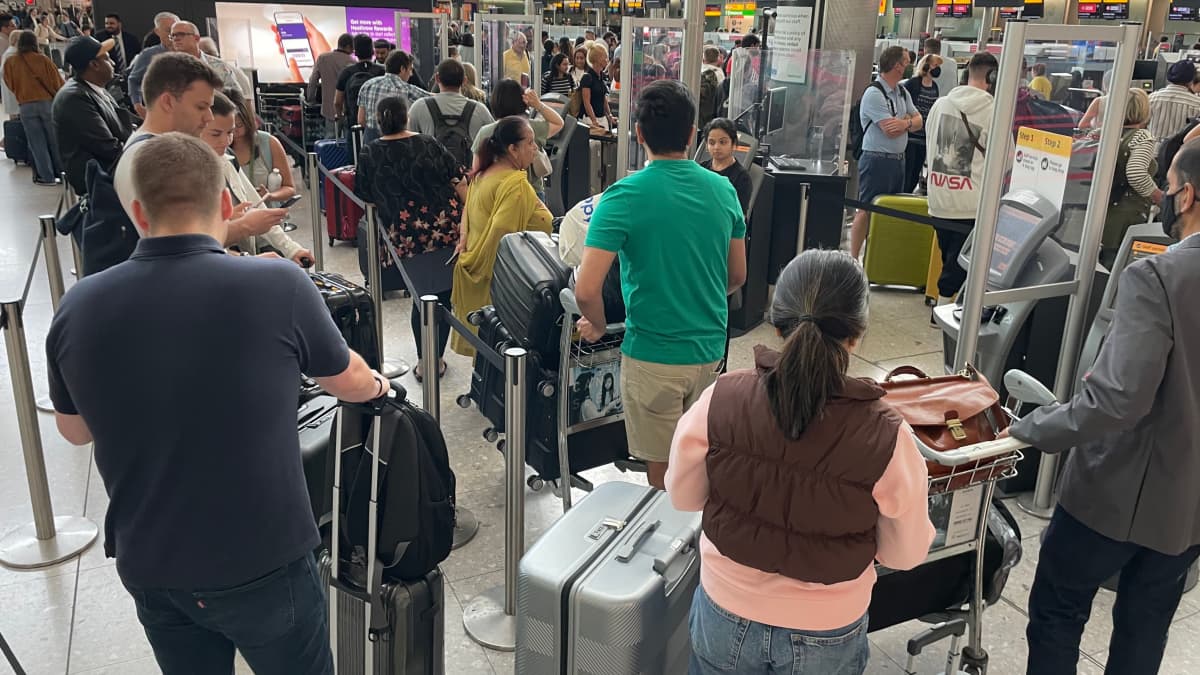 Resenärer med bagage köar på Heathrow flygplats.