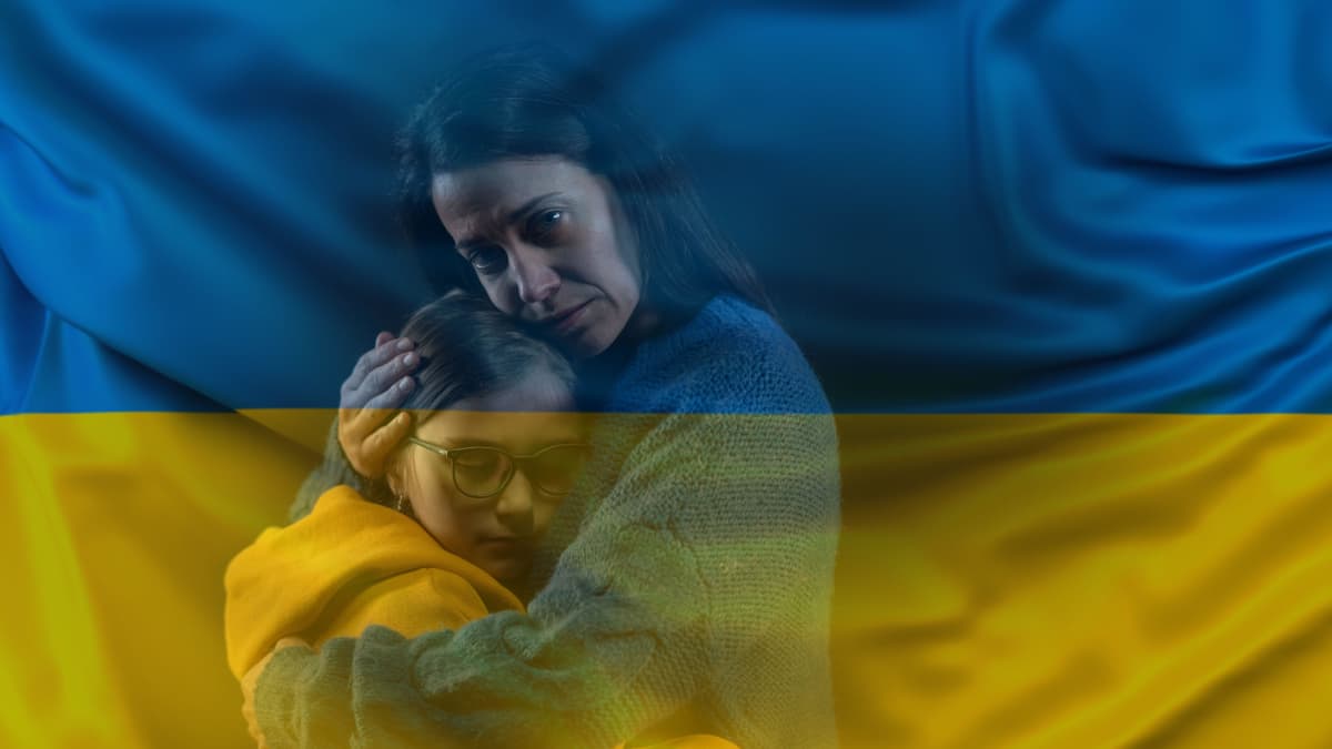 Nainen syleilee kouluikäistä lasta, päällekkäin valotettuna kuvassa ukrainan lippu.