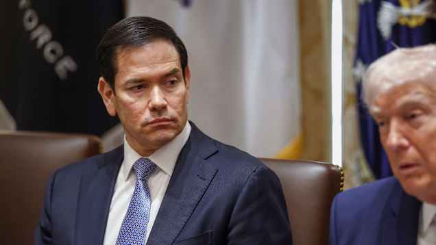 Marco Rubio istuu neuvottelupöydässä, katsoo sivulleen. 