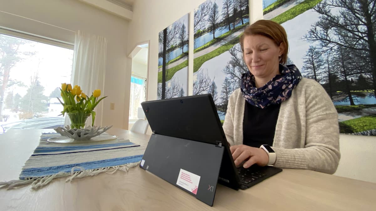 Nainen tekee tietokoneella etätöitä kotonaan