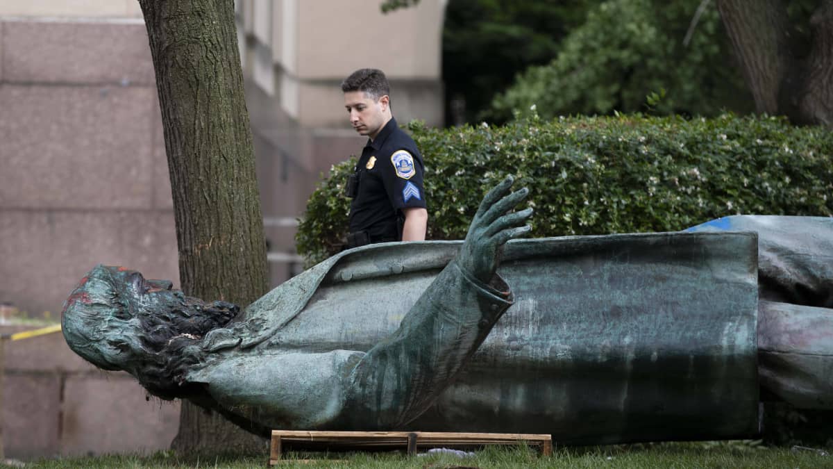 Poliisi katsoo maahan kaadettua patsasta.