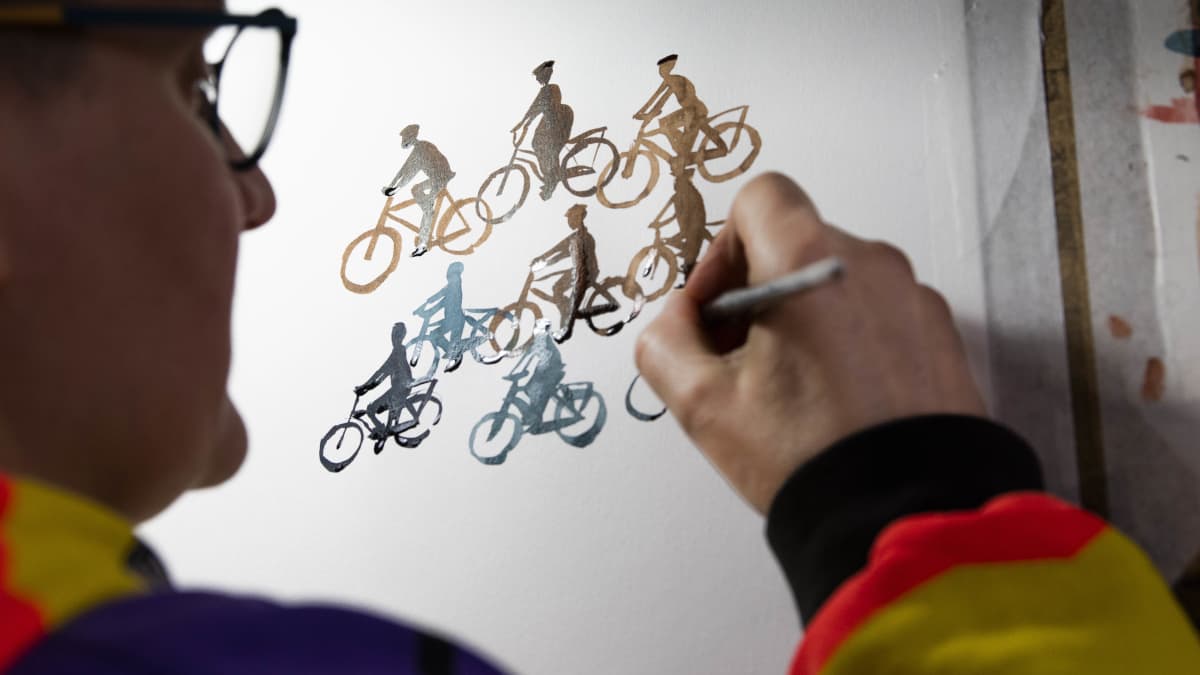 Sarjakuvataiteilija Tiitu Takalo maalaa kapealla siveltimellä pyöräilijöitä.
