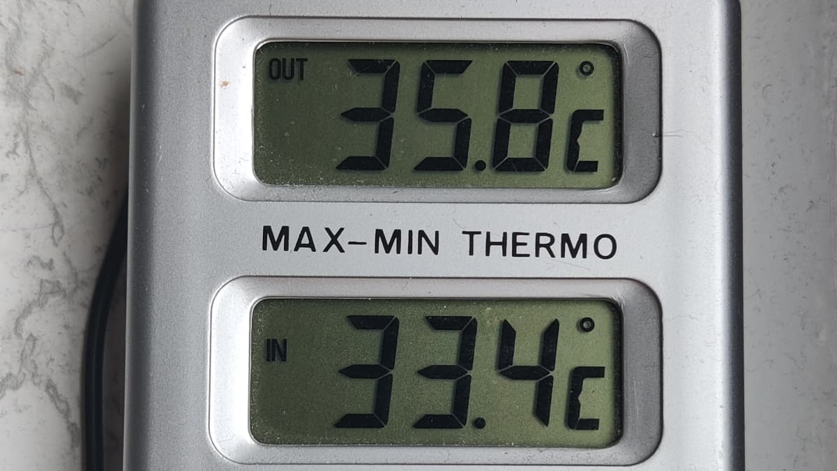 Lämpömittarin lukema näyttää ulkona 35,8 astetta ja sisällä 33,4 astetta.